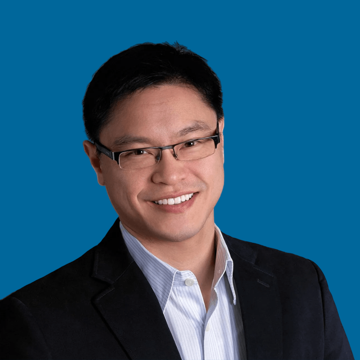 Jason Fung smiling at camera against blue background